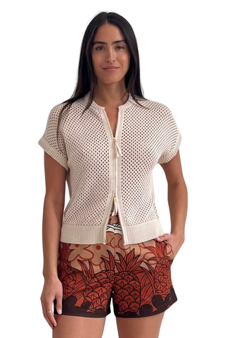 Model wearing the Trina Turk Hana Zip Cardigan in Bonita Beige featuring textured cotton knit, dolman sleeves, and zip-front closure paired with printed shorts
