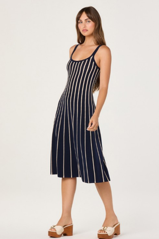 Model wearing the ASTR Irecia Sweater Dress in Navy Stripe featuring a scoop neckline, tank silhouette, soft knit fabric, and cream vertical stripes on a classic navy midi dress.