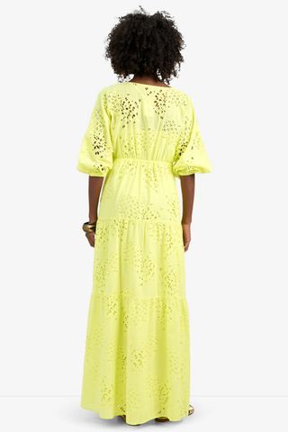 Model wearing the Trina Turk Arco Iris Dress in Citrus featuring pineapple eyelet embroidery, balloon sleeves, empire waist, and tiered maxi skirt