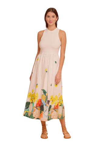 Model wearing the Olivia by Livro Elsie Dress in Farmer's Market, featuring a cream ribbed bodice, racerback silhouette, flowing cotton midi skirt, and a colorful produce-inspired print along the hem.