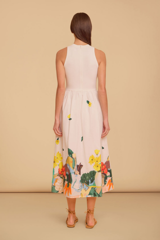 Model wearing the Olivia by Livro Elsie Dress in Farmer's Market, featuring a cream ribbed bodice, racerback silhouette, flowing cotton midi skirt, and a colorful produce-inspired print along the hem.