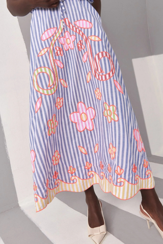Celia B Kailen Dress in Multi featuring blue striped cotton fabric, colorful floral embroidery, ruffle trim, and tie shoulder straps