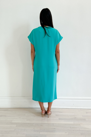 Woman wearing a tropical teal midi dress with short sleeves and relaxed silhouette from Trina Turk on a white background.