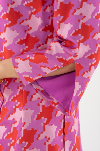 Emily McCarthy Ashley Ann Top in Houndstooth featuring a vibrant pink, red, and lavender pattern with flared sleeves and contrast trim.