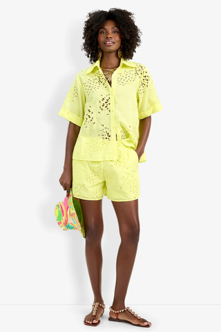 Model wearing the Trina Turk Triennale Top in Citrus featuring pineapple eyelet embroidery, short sleeves, and lace-up back detail with matching shorts