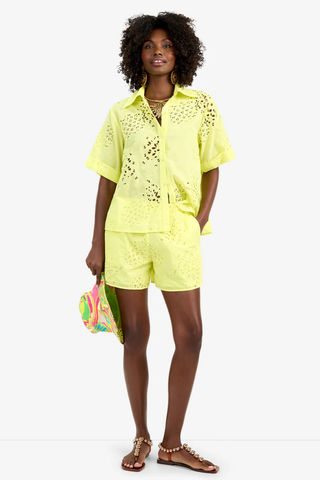 Model wearing the Trina Turk Triennale Top in Citrus featuring pineapple eyelet embroidery, short sleeves, and lace-up back detail with matching shorts
