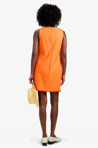 Model wearing the Trina Turk Waveson Dress in Orange Oasis featuring textured jacquard fabric, fringe-trim patch pockets, sleeveless styling, and a V-neckline